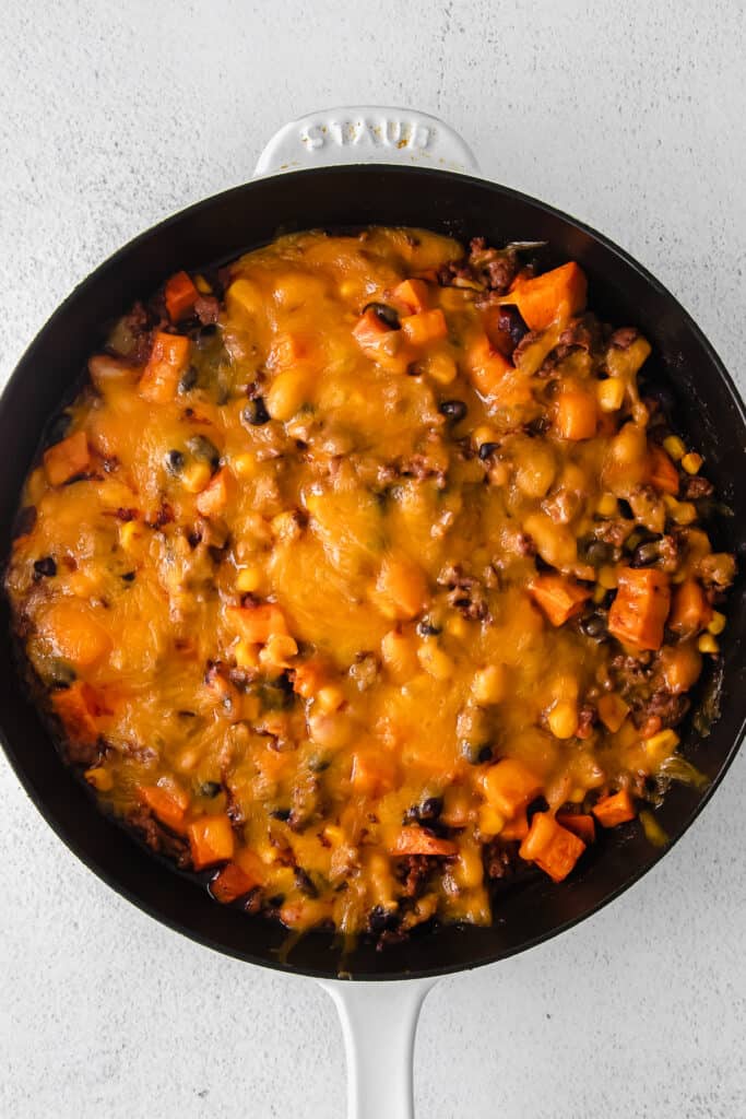 turkey sweet potato enchilada skillet topped with melted shredded cheese