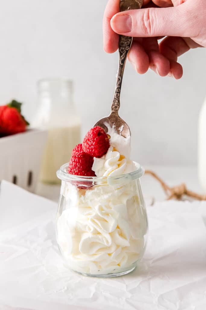 A spoon full of whipped cream and fresh raspeberries. 