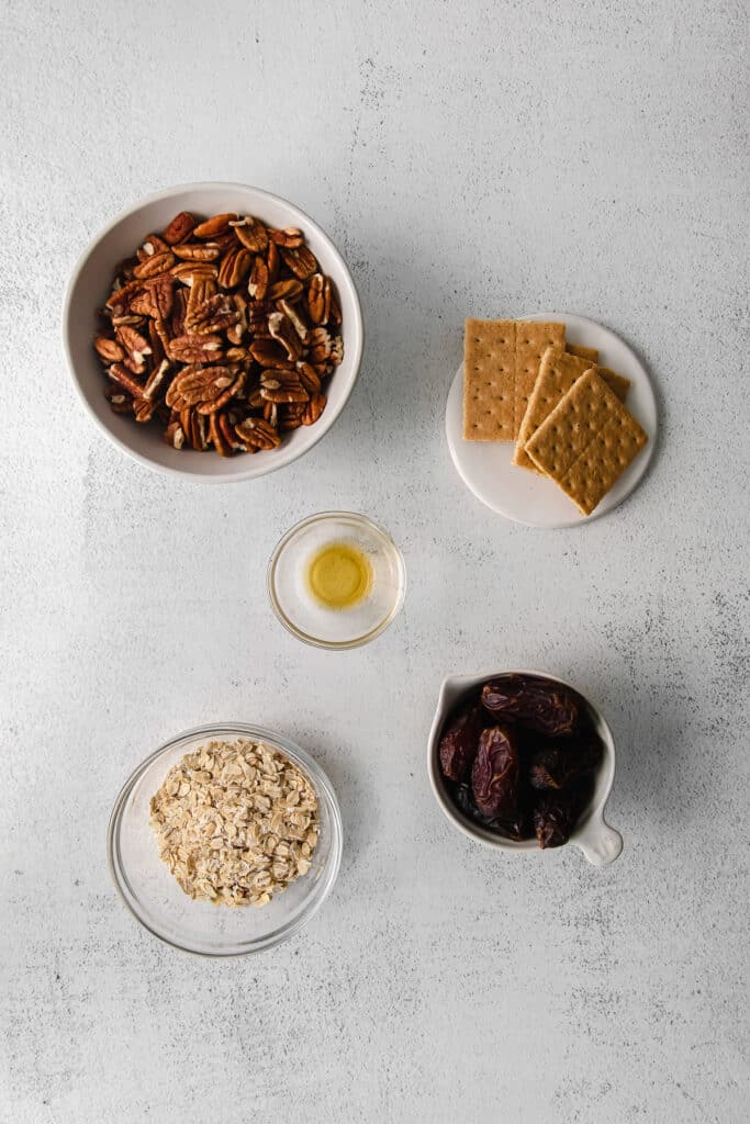 Pecans, graham crackers, vanilla extract, dates and oats in a bowl. 