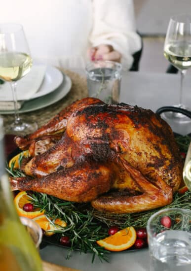 A turkey is sitting on a table with wine glasses.