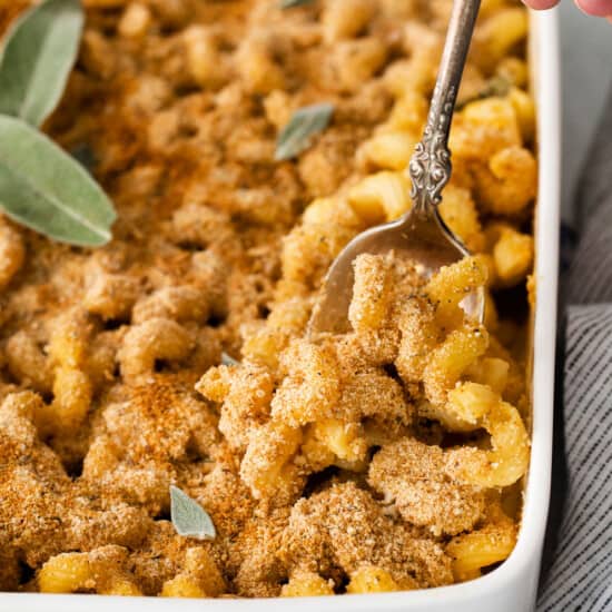 Butternut squash mac and cheese with sage in a white casserole dish.