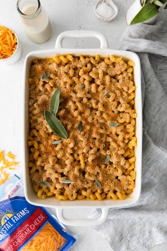 butternut squash mac and cheese in a casserole dish topped with fresh sage