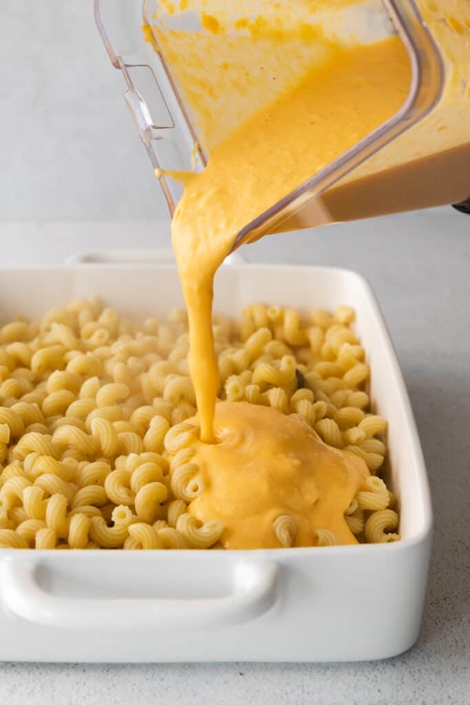 butternut squash sauce being poured over cavatappi noodles