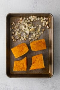 Roasted sweet potato slices combined with butternut squash on a baking sheet.