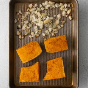 Roasted sweet potato slices combined with butternut squash on a baking sheet.
