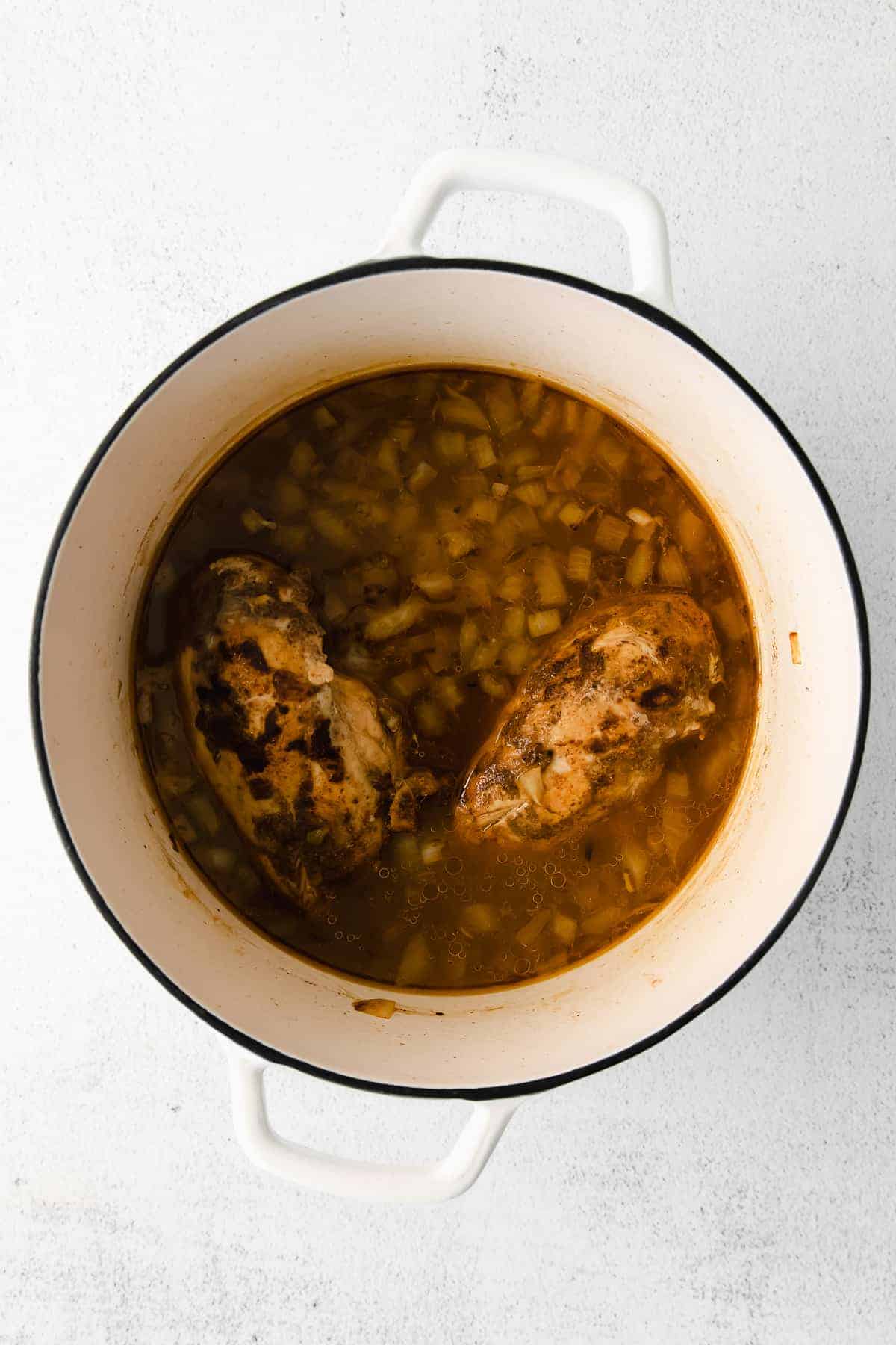 Chicken breasts cooking in a big pot.