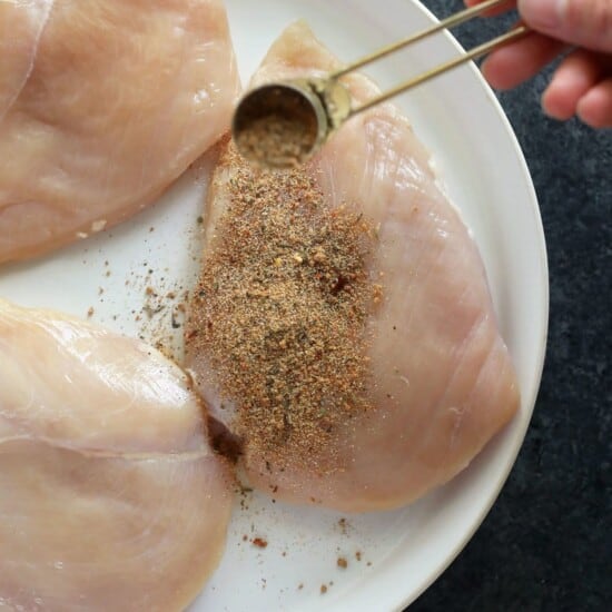 seasoning chicken breast on plate.