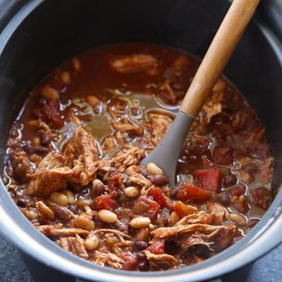 Crockpot chicken chili with a wooden spoon in it.