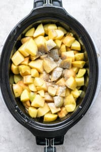 A crock pot filled with chopped apples.