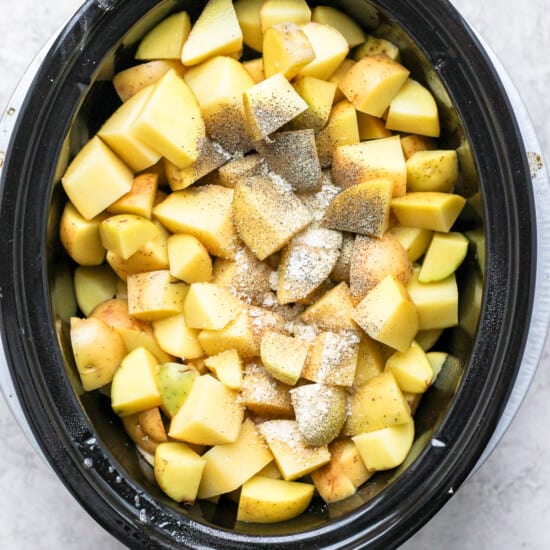A crock pot filled with chopped apples.