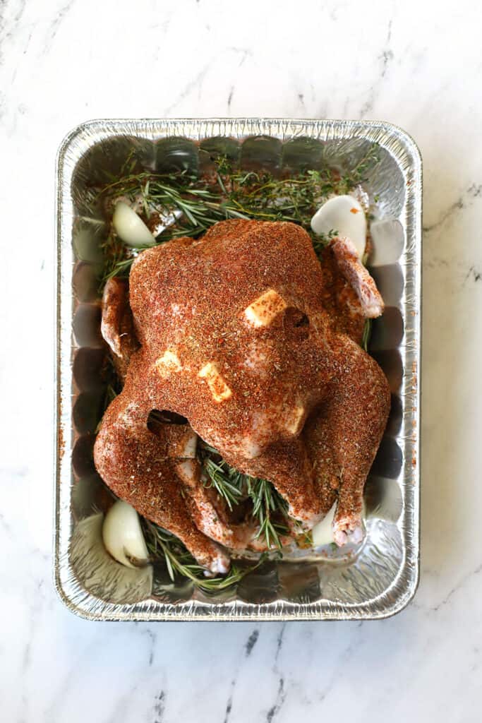 Seasoning smoked turkey in a turkey container. 