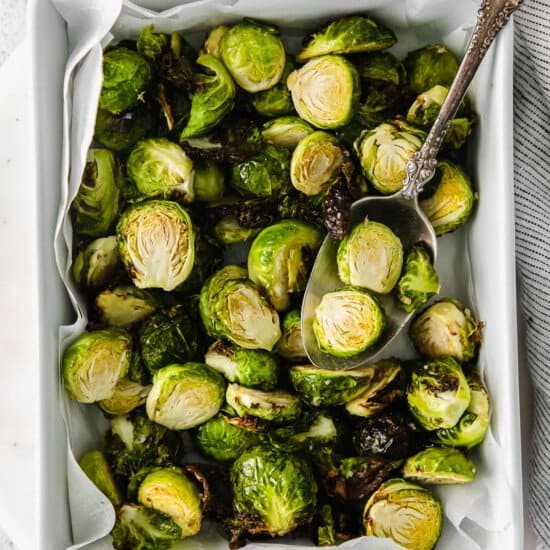 Roasted brussels sprouts in a baking dish with a spoon.
