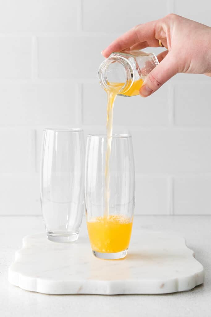 orange juice being poured into stemless champagne flutes
