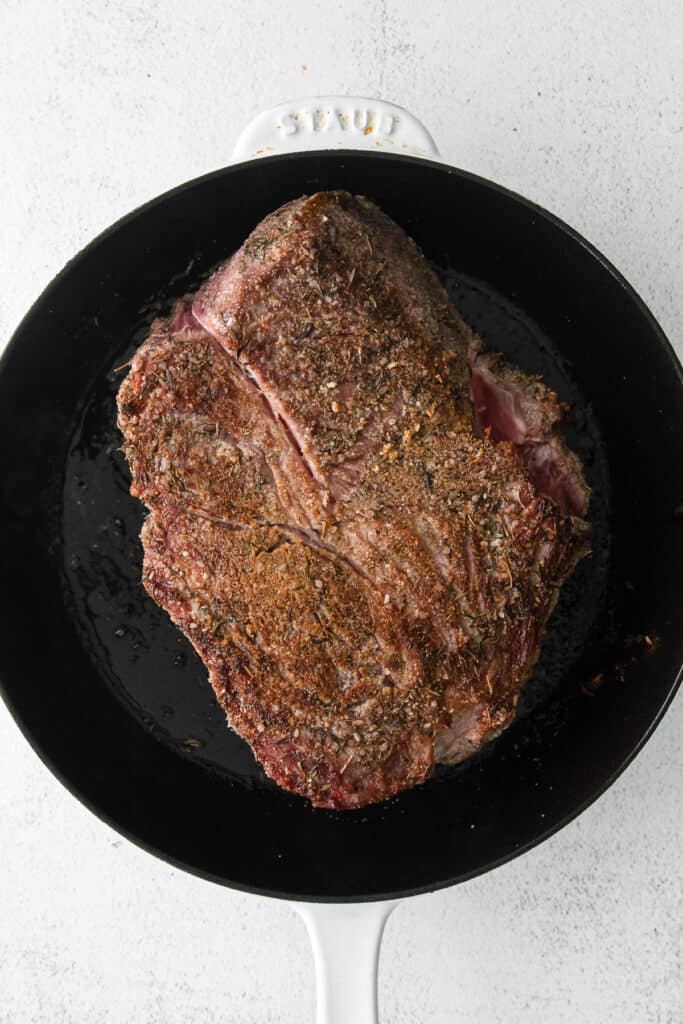 chuck roast being seared in a cast iron skillet