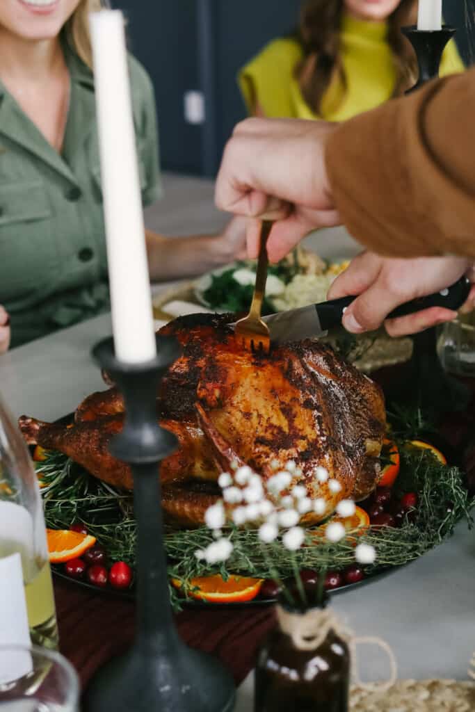 man carving a turkey at a thanksgiving table