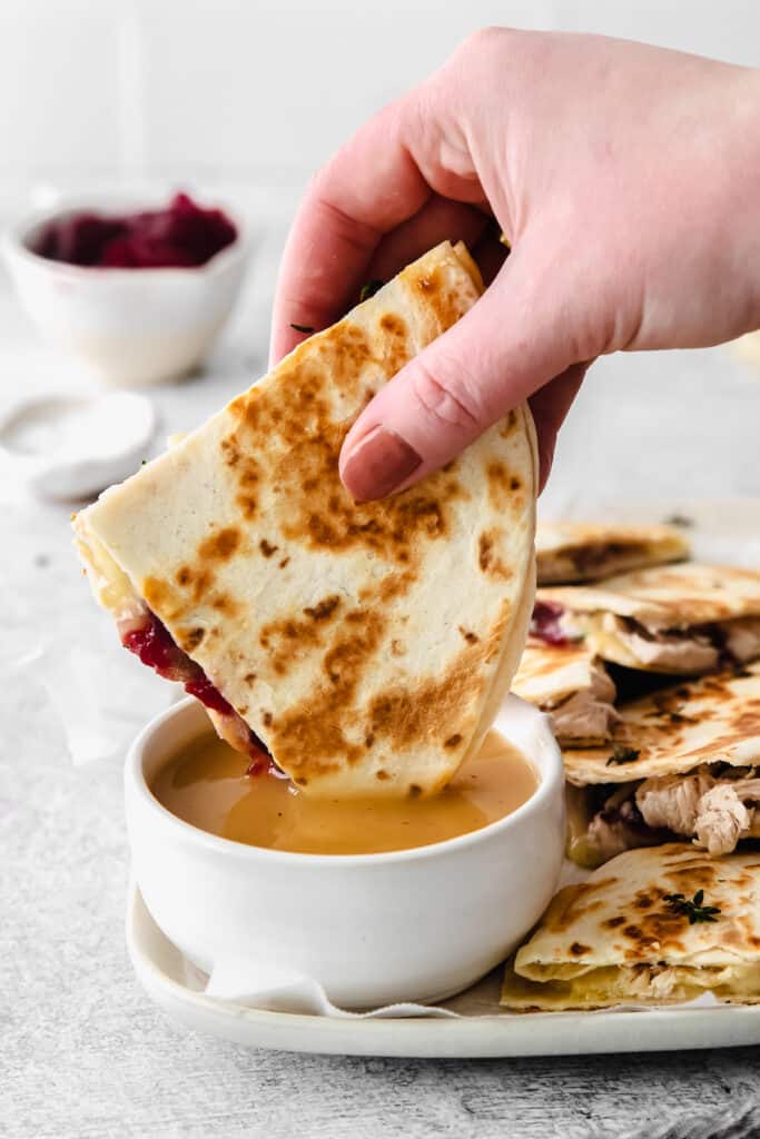 leftover thanksgiving turkey quesadilla being dipped into gravy