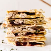 A stack of leftover Thanksgiving turkey quesadillas with cranberry sauce.