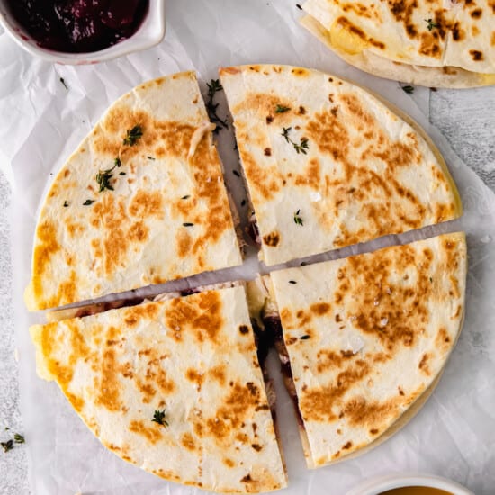 Leftover Thanksgiving turkey quesadilla topped with cranberry chutney on a white plate.