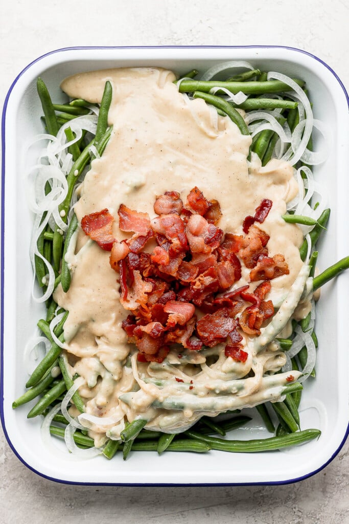 green bean casserole with bacon in a casserole dish ready to be baked