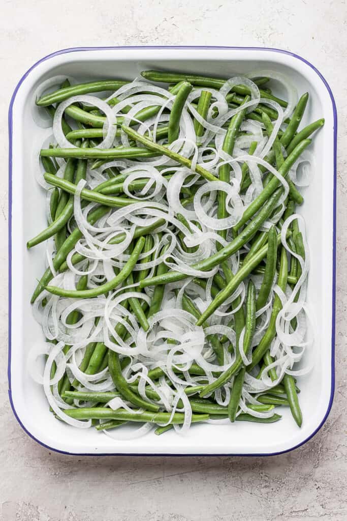 green beans and sliced onions in a casserole dish