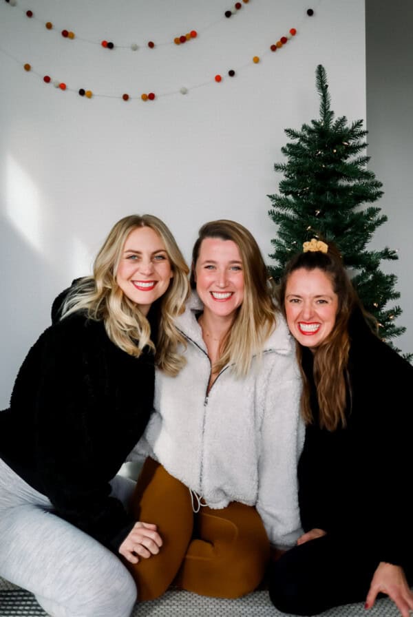 Three women showcasing their Lululemon holiday wish list in front of a Christmas tree.