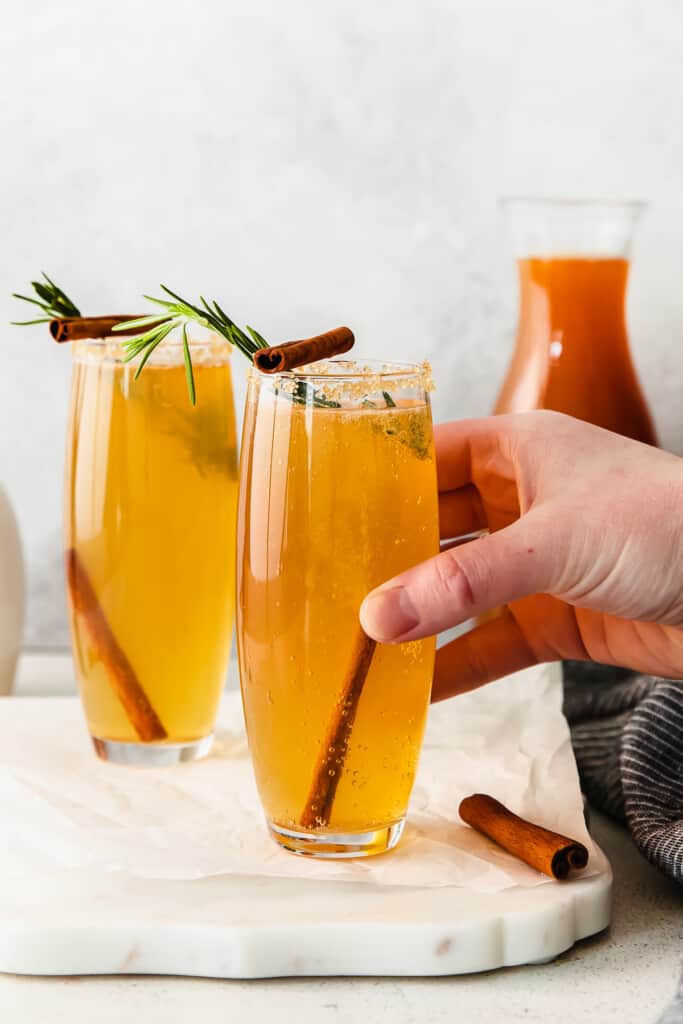 A hand holding an apple cider mimosa.