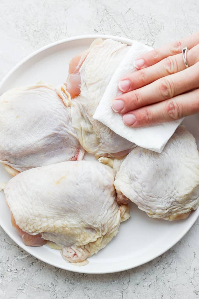 patting chicken thighs with paper towel