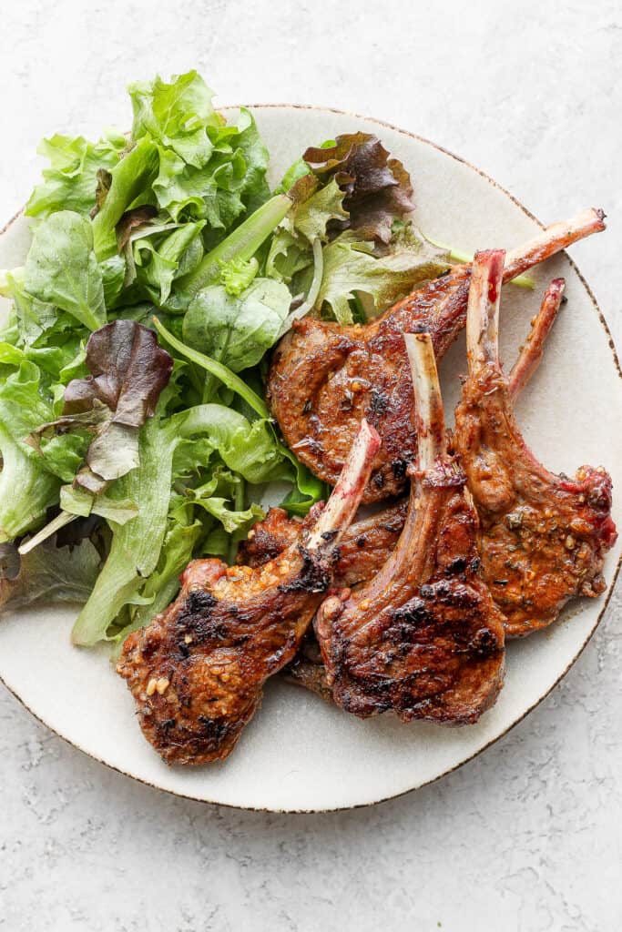 pan seared lamb chops on a plate next to a salad
