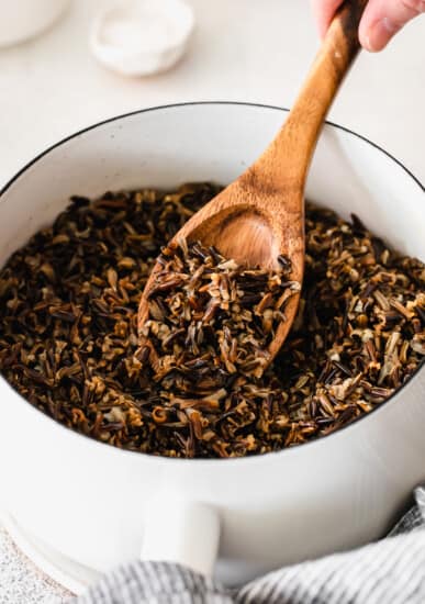 wild rice in a pot being stirred with a wooden spoon