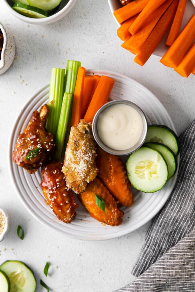 Chicken wings on plate with vegetables. 