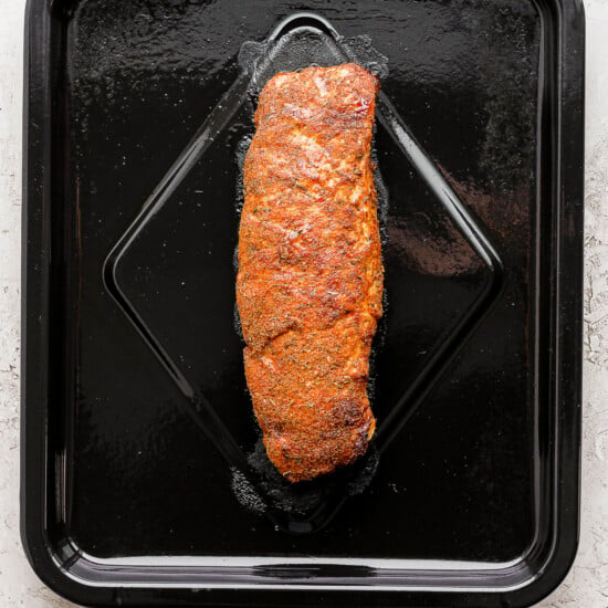 A piece of salmon cooked in an air fryer, served on a black tray.