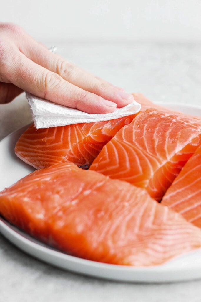 patting raw salmon with paper towel.