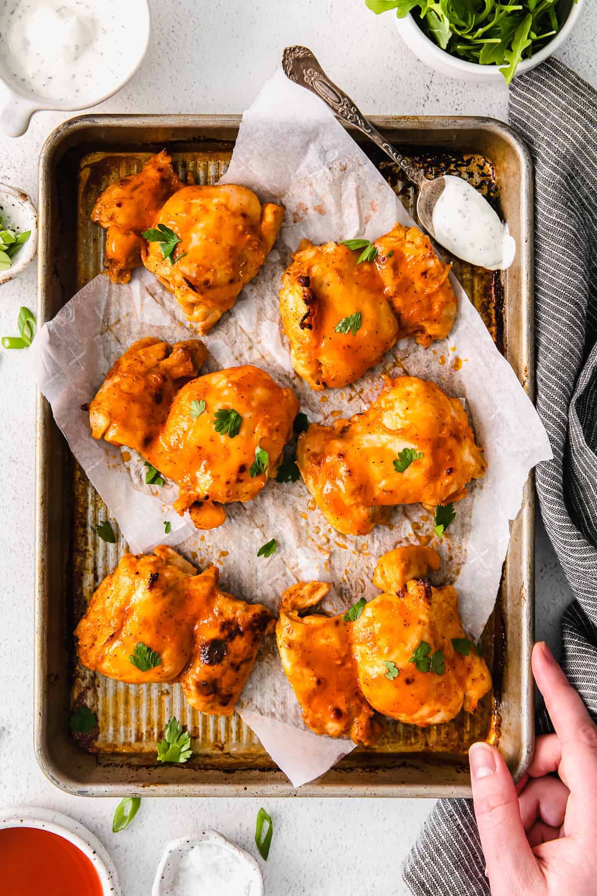 buffalo baked boneless chicken thighs on a baking sheet