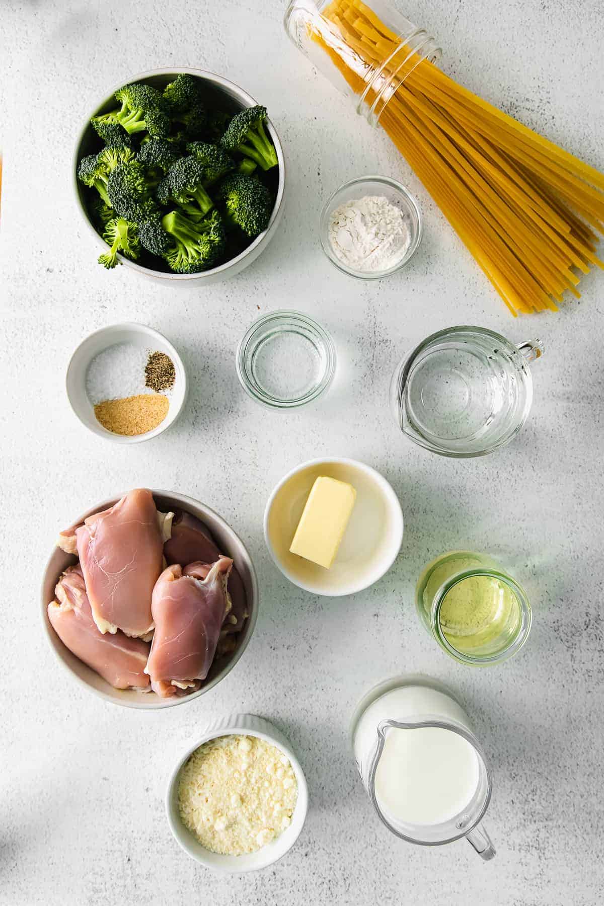 Chicken thighs, butter parmesan, garlic, milk, and few other ingredients in bowls. 