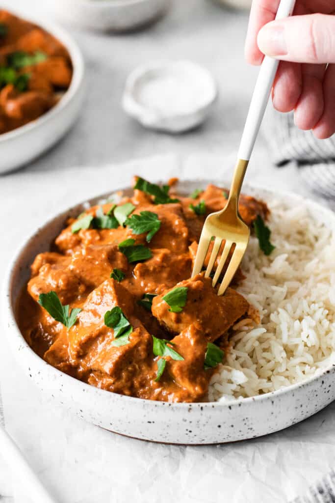 A fork digging into butter chicken. 