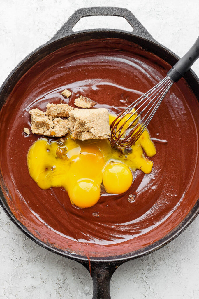 egg yolks and brown sugar being added to the flourless chocolate skillet cake batter