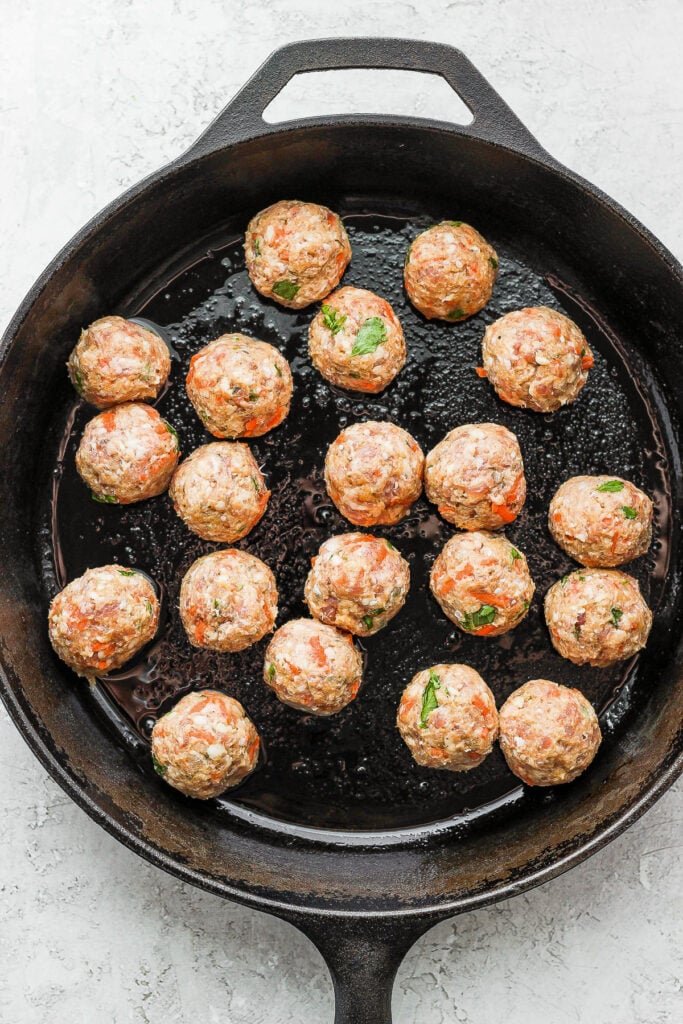 Browning meatballs in a cast iron skillet. 