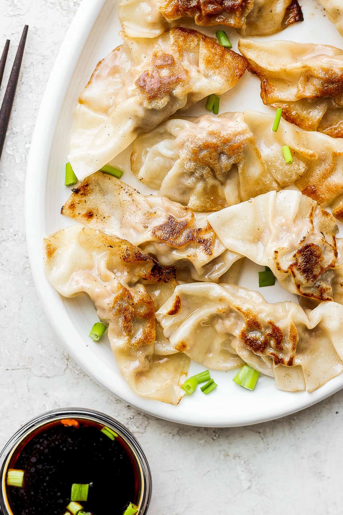 pork dumplings on a plate with fresh green onions