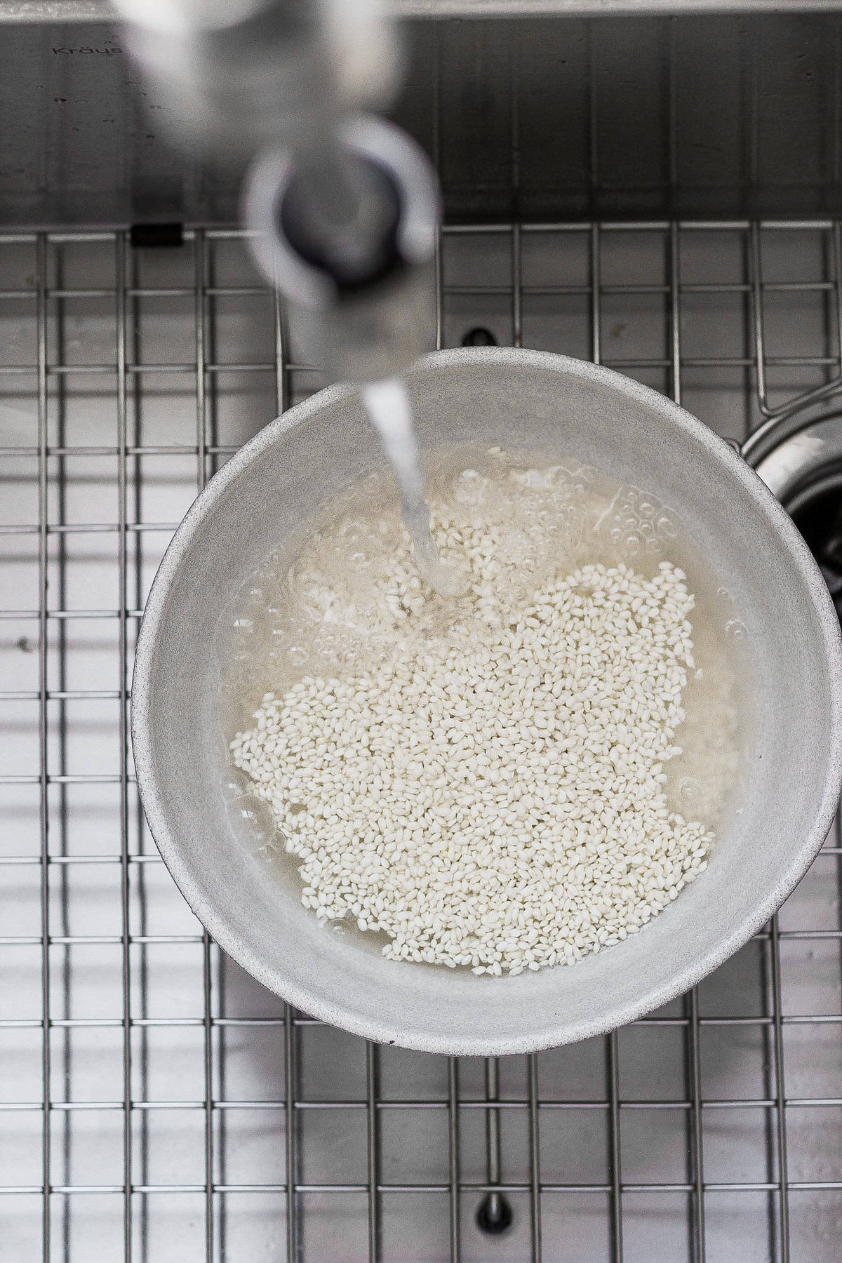 rinsing sticky rice in a bowl in the sink