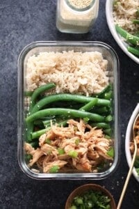 A bowl of rice and green beans with crock pot honey garlic chicken in a plastic container.