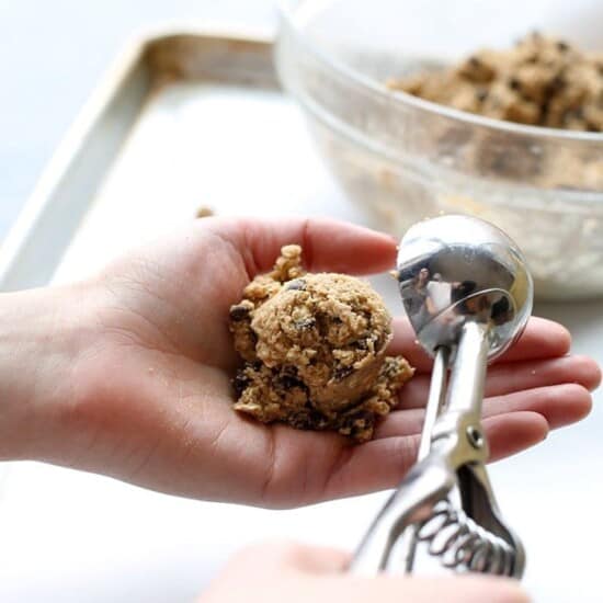 A person holding a spoonful of healthy oatmeal cookie dough.