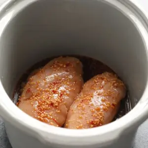 raw chicken and sauce in crock pot.