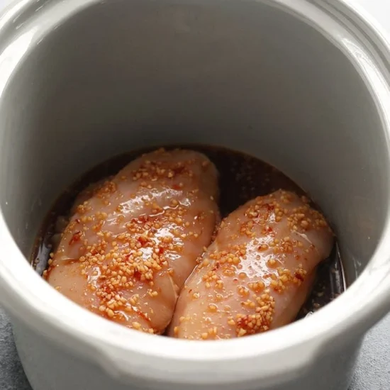 raw chicken and sauce in crock pot.