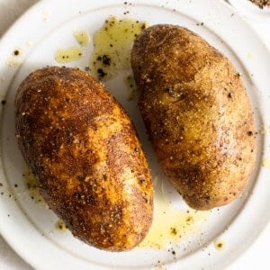Two roasted potatoes on a white plate.