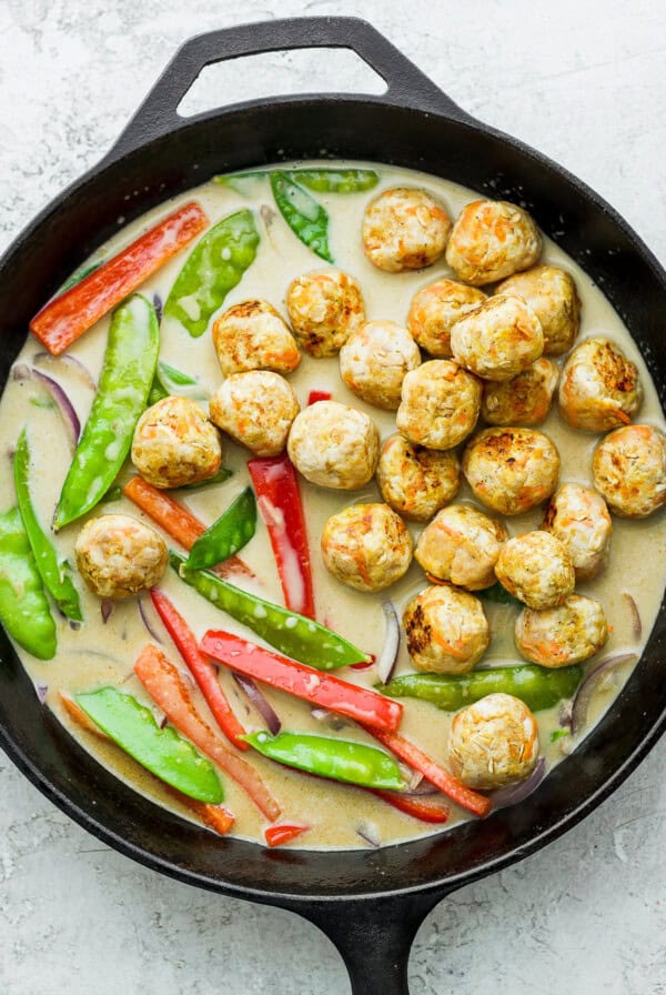 Green curry chicken meatballs in a cast iron skillet.