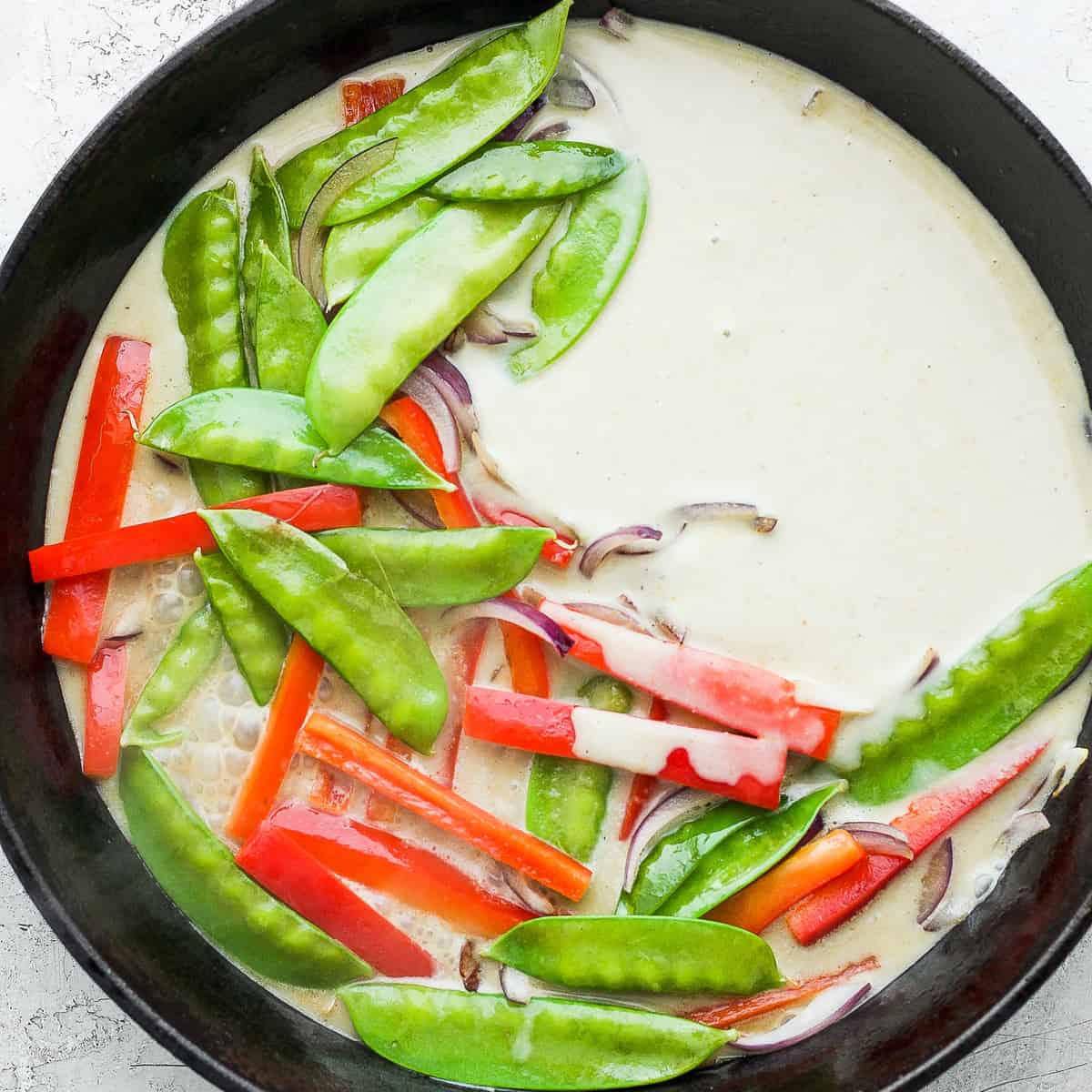 Green curry and vegetables in a cast iron pan. 