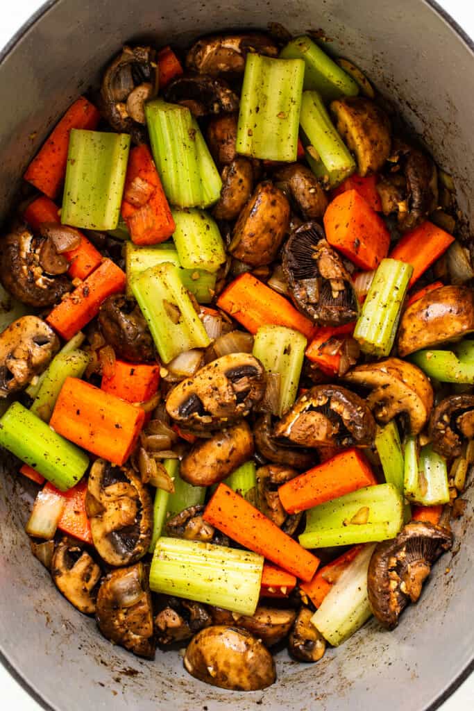 Carrots, celery, and mushrooms in a Dutch oven. 