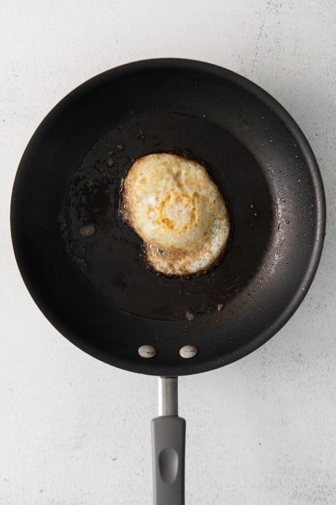 An over hard egg in a nonstick pan. 