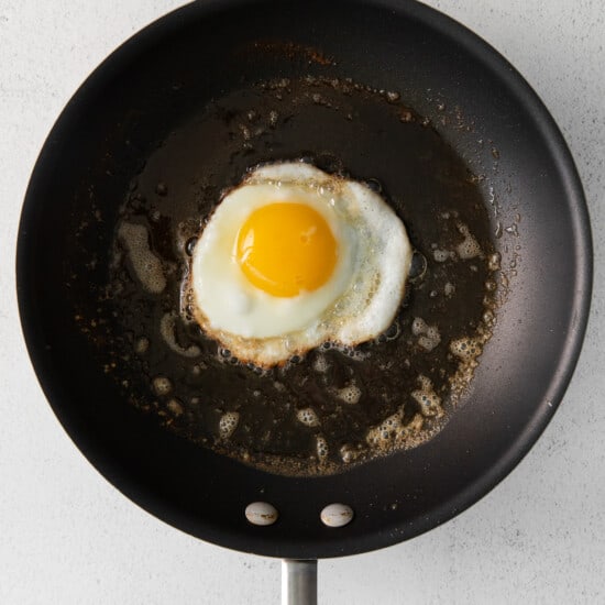 Et stekt egg i en stekepanne på en hvit bakgrunn.