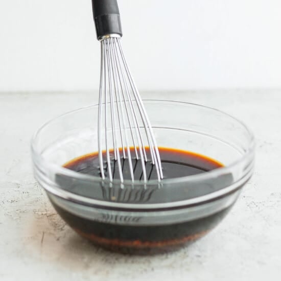 A whisk in a bowl with a sauce.